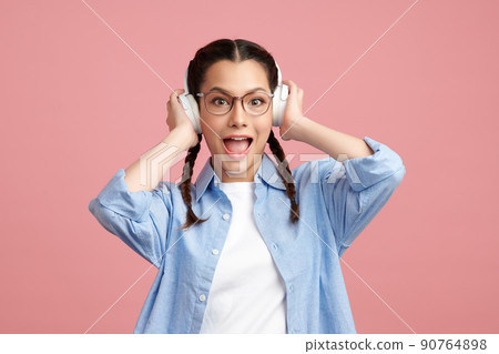 Cute Asian girl is wearing headphone and standing on pink background with happy face, blank copy space for your advertising content. 90764898