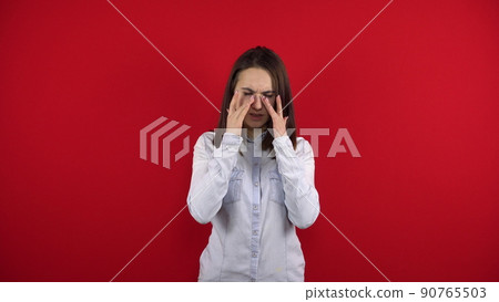 The young woman has a sore nose, she touches it with her hand. Shooting on a red background. 90765503