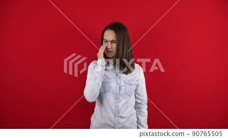 The young woman has a sore nose, she touches it with her hand. Shooting on a red background. 90765505