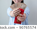 Asian women are glad to receive a lot of extra money from red envelopes. 90765574