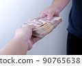 Image of a man's hand giving a large amount of money to a woman's hand (Thai banknotes)   90765638