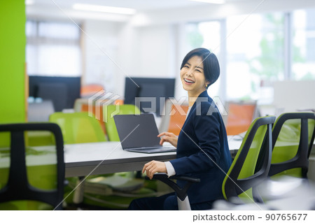 A business woman in a suit who works at the office desk A business woman in a suit who works at the office desk 90765677