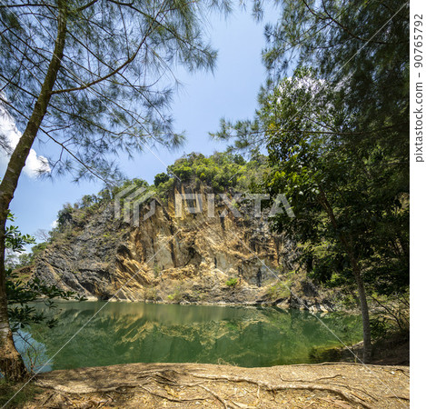 Emerald green pond.Caused by digging limestone mines Blue sky and white clouds , Tons of wood covered. Emerald green pond.Caused by digging limestone mines Blue sky and white clouds , Tons of wood covered. 90765792