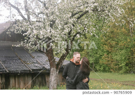 Sensual woman and man in cherry bloom. Couple in love in blossoming garden in spring. Love and romance, relationship, happy family outdoors 90765909
