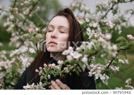 portrait of a beautiful young woman in the spring garden among apple blossom.  90765948