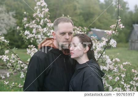 Sensual woman and man in cherry bloom. Couple in love in blossoming garden in spring. Love and romance, relationship, happy family outdoors 90765957