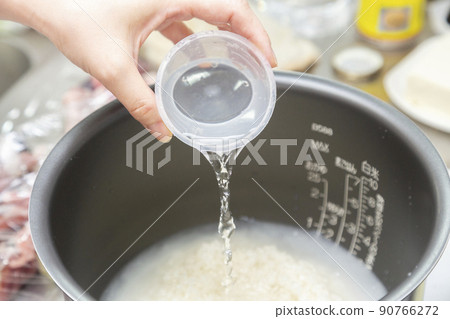 A woman who puts water in the rice cooker's pot 90766272