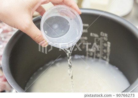 A woman who puts water in the rice cooker's pot A woman who puts water in the rice cooker's pot 90766273
