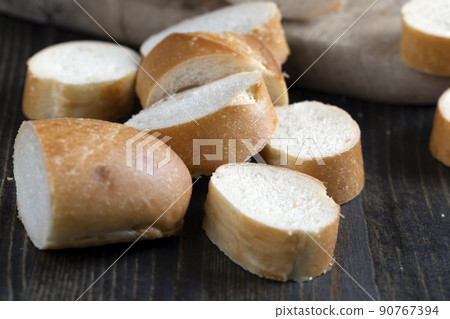 wheat baguette cut into pieces on a cutting board 90767394