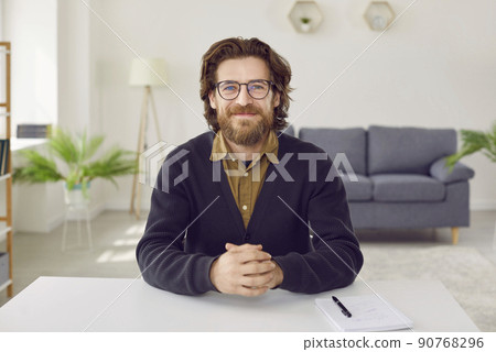 Portrait of happy businessman or teacher sitting at desk during online conference Portrait of happy businessman or teacher sitting at desk during online conference 90768296