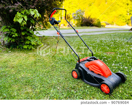 Lawn mower on green grass in a modern garden. Territory care. Selective focus Lawn mower on green grass in a modern garden. Territory care. Selective focus 90769084
