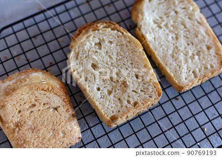 Baked Ruddy Wheat Bread Brick on sourdough with flax seeds on a black grid, on gray concrete background. 90769193