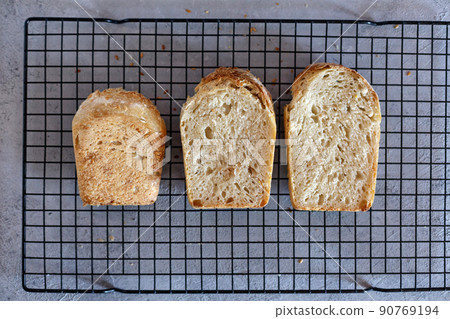 Baked Ruddy Wheat Bread Brick on sourdough with flax seeds on a black grid, on gray concrete background. 90769194