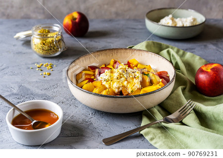 Healthy fruit salad with nectarine, ricotta cream with pistachios and honey 90769231