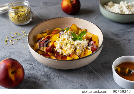 Healthy fruit salad with nectarine, ricotta cream with pistachios and honey 90769243