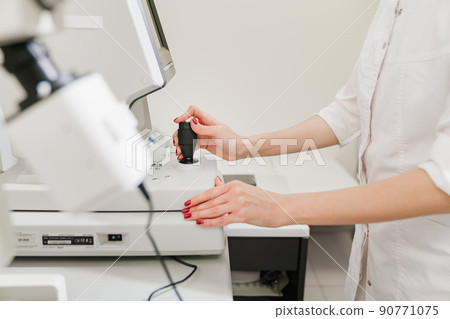 doctor examines eyes on screen of autorefractometer.  90771075