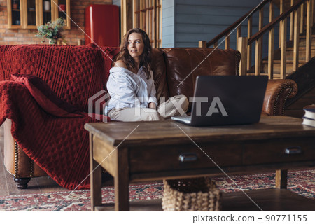 Young woman sitting at home on the sofa 90771155