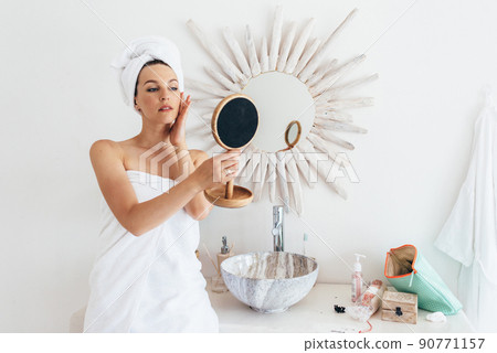 Young woman with a mirror in the bathroom 90771157