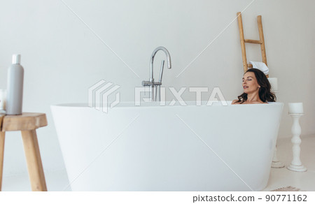 Woman resting in bathtub with eyes closed Woman resting in bathtub with eyes closed 90771162