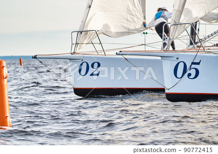 Bowsprits of sailing yachts in sailing regatta at sunset, still water, the clear sky, hot racing 90772415