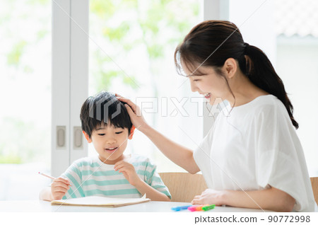 Boy and mother studying in the living room 90772998