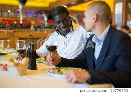 Two unhappy male friends talking together in a restaurant 90776790