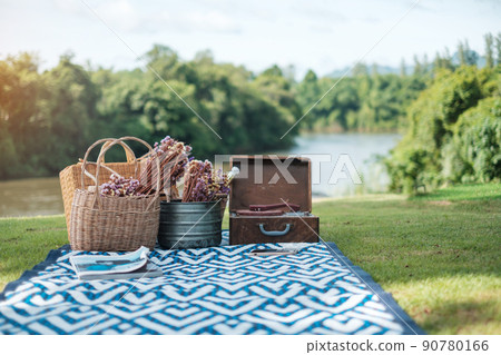 picnic set in the park near river, dried flowers, baskets wine bottle, book and retro gramophone vinyl record. Summer, spring and vacation concept picnic set in the park near river, dried flowers, baskets wine bottle, book and retro gramophone vinyl record. Summer, spring and vacation concept 90780166