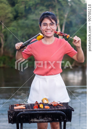 Happy woman with delicious grilled meat and BBQ in outdoor. Barbecue, Party, lifestyle and picnic concept 90780218