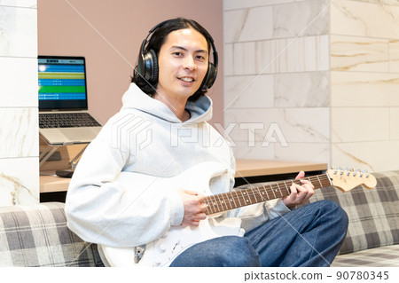 Young man playing white electric guitar Young man playing white electric guitar 90780345