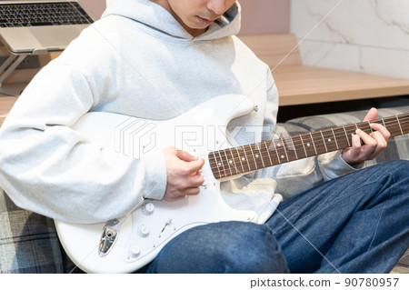 Young man playing white electric guitar Young man playing white electric guitar 90780957