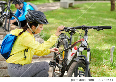 Young Woman Checking Bicycle Wheels 90782634