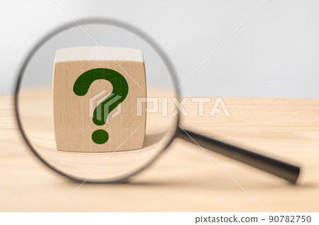 Search for an answer to question. Magnifying glass with question mark in focus on wooden cube. Research, searching or investigating something 90782750