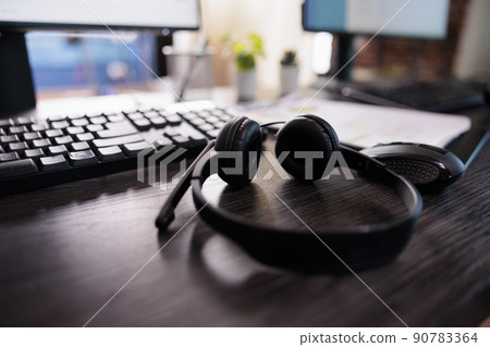 Telemarketing client service equipment on helpdesk in office, telework headset with microphone. Call center customer support helpline on reception desk with computers. Close up. 90783364