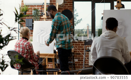 Modern artist analyzing vase drawing by senior woman in art school lesson, teaching imagination skills to draw creative model and design on canvas. Artistic sketch. Tripod shot. 90783555