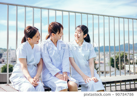 A close female doctor and nurse (smile) talking on the roof of the hospital A close female doctor and nurse (smile) talking on the roof of the hospital 90784786