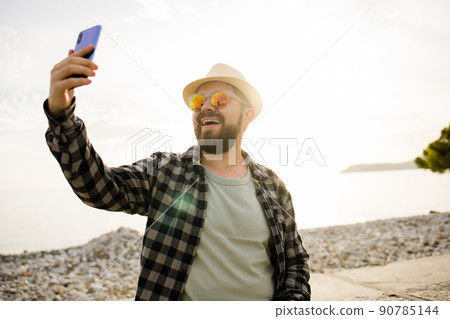 Traveler or tourist take self photo with smartphone on sea view - alone travel and technologies and millennial or gen z lifestyle concept. 90785144