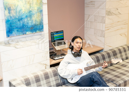 Young man playing white electric guitar Young man playing white electric guitar 90785331
