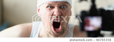 Man screaming on camera while performing exercise at home Man screaming on camera while performing exercise at home 90785356