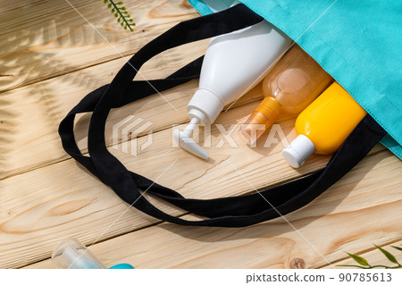 Sunscreen cream bottles in beach bag on wooden background Sunscreen cream bottles in beach bag on wooden background 90785613