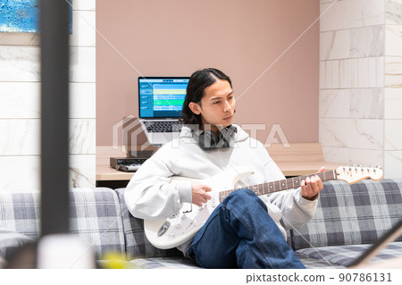 Young man playing white electric guitar 90786131