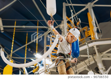 cute little boy climbing in adventure park passing obstacle course. high rope park indoors 90786550