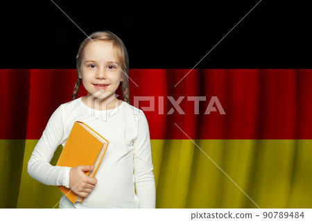 Education and school in Germany. Beautiful cute little kid girl with book against German flag Education and school in Germany. Beautiful cute little kid girl with book against German flag 90789484