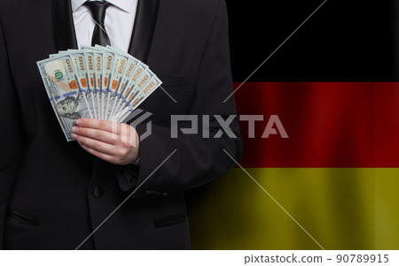 German business man hand holding US 100 dollar bills against flag of Germany background 90789915