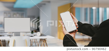 Modern office building workplace interior with a businesswoman's hands holding a smartphone mockup 90790462