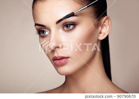 Beautiful brunette woman paints the eyebrows 90790670