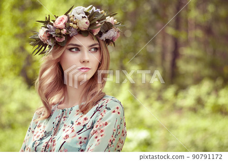 Beautiful blonde woman with flower wreath on her head Beautiful blonde woman with flower wreath on her head 90791172