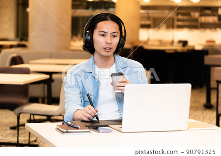 A man wearing headphones and working on a pen tablet 90791325