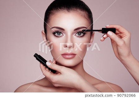 Beautiful brunette woman paints the eyelashes 90792066