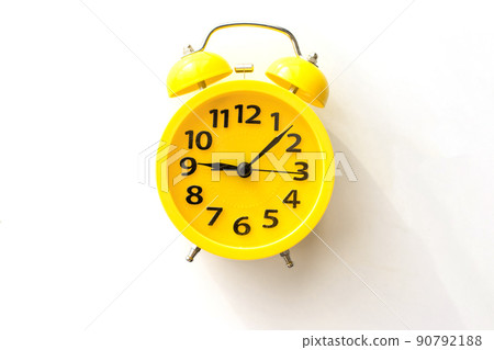 A yellow alarm clock lies on a white table, top view 90792188