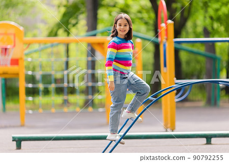 a girl in a bright striped jumper and jeans, stand on the childrens stairs on the playground a girl in a bright striped jumper and jeans, stand on the childrens stairs on the playground 90792255